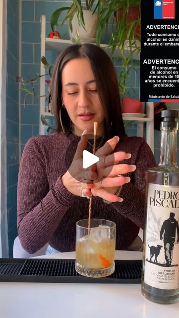 Nina preparando un trago con una botella de Pedro Piscal